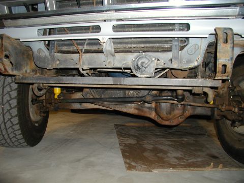 1986 Ford Bronco - Undercarriage view of a vehicle, revealing the front axle, steering components, and radiator assembly.