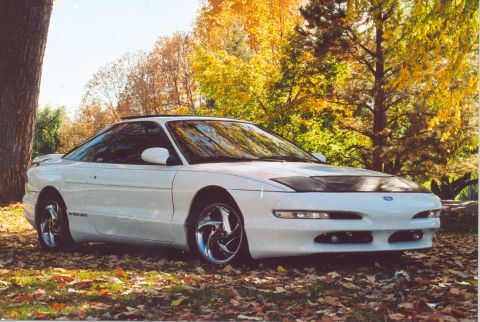 1996 Ford Probe - A white 1996 Ford Probe is parked outdoors with colorful autumn trees behind it.
