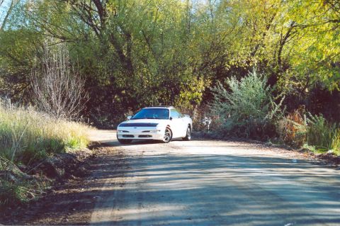 1996 Ford Probe - White 1996 Ford Probe sits on a dirt road surrounded by autumn foliage.