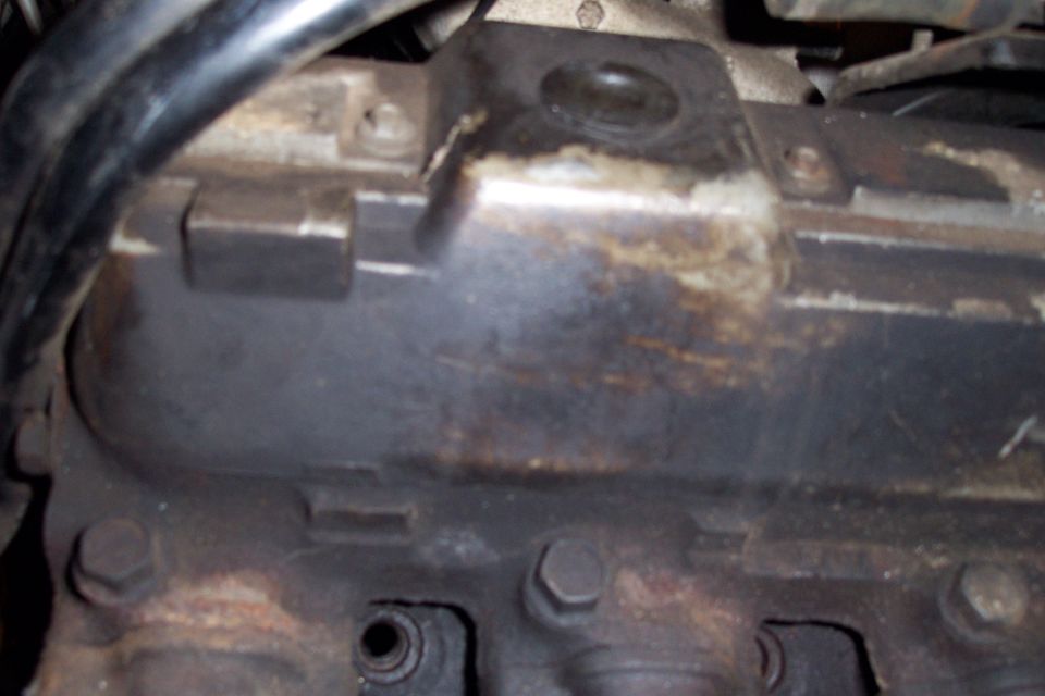 Close-up of a dark, greasy engine component with bolts visible