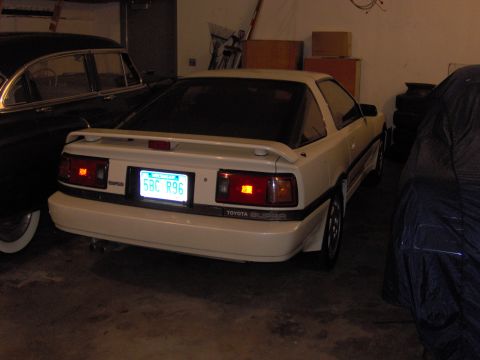 1994 Ford Probe - A white Toyota Supra is parked in a garage, with other vehicles nearby. The rear of the car is visible.