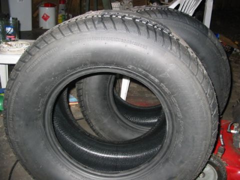 1985 Ford LTD Crown Victoria - A stack of four tires are shown, with some text visible on their sidewalls.