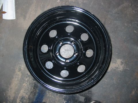 1985 Ford LTD Crown Victoria - Black steel wheel with multiple circular cutouts, likely for a car or truck.