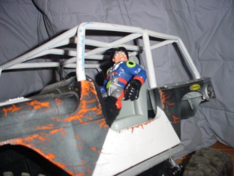 1988 Ford Bronco - This toy RC crawler features a driver figure in a roll cage, with a distressed paint scheme.
