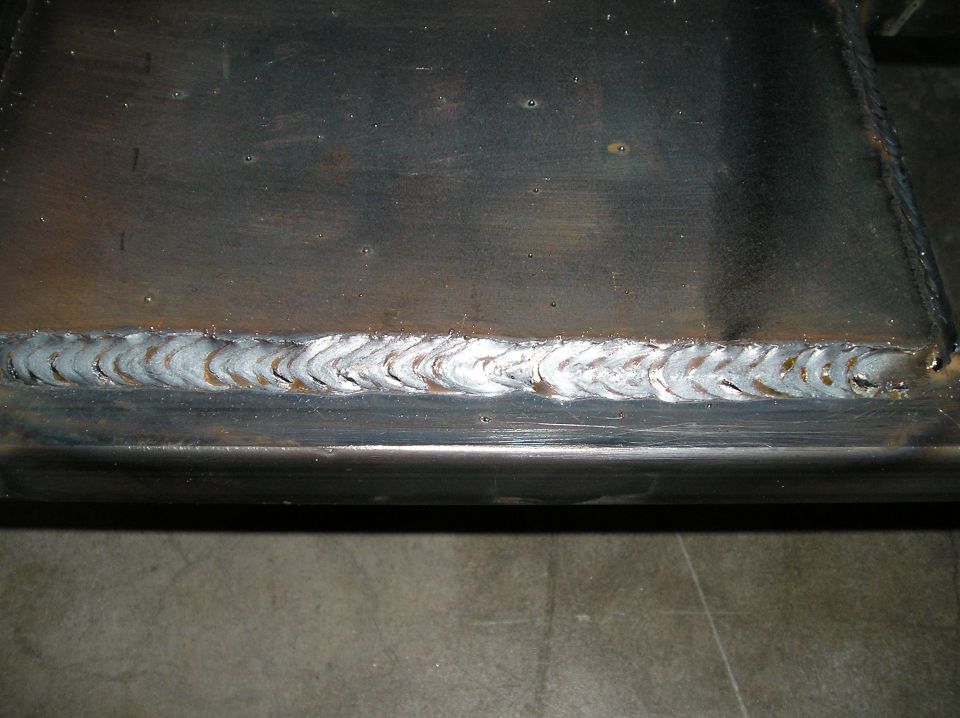 Close-up of stacked-dime weld bead joining steel plate with heat discoloration