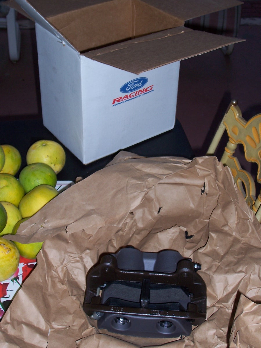 Ford Racing brake caliper in packaging with oranges and a box