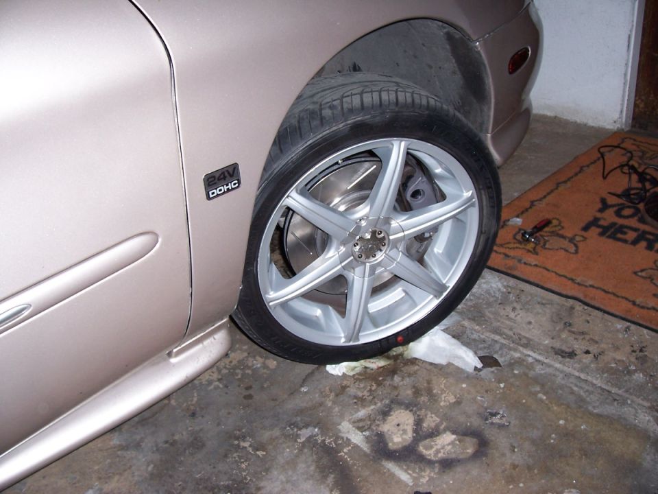 Car's front wheel and fender with a '24V DOHC' badge visible