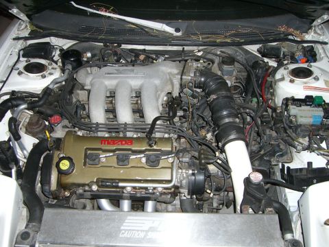 1996 Ford Probe - The engine bay of a vehicle, a Mazda engine with its cover and intake system visible.