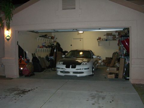 1996 Ford Probe - A white 1996 Ford Probe with a black hood and racing stripes is parked inside a garage.