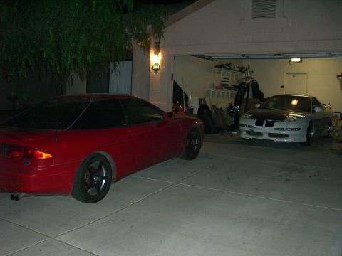 1996 Ford Probe - Two sports cars, including a 1996 Ford Probe, are parked in a garage at night.