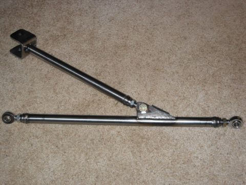 1991 Ford Explorer - A fabricated bare-steel suspension link assembly laid on tan carpet, built from tubular bars with threaded rod-end (heim) joints, a welded…