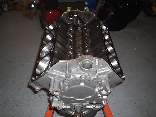 Bare aluminum V-engine block sitting on an engine stand in a garage, valley and main caps showing