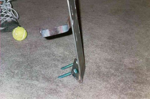 1994 Ford Bronco - A metal bracket with screws and a tennis ball are on a carpeted surface.
