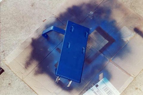 1994 Ford Bronco - Metal bracket painted blue, placed on cardboard with spray paint marks.