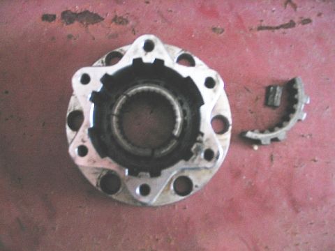 1986 Ford F-150 - A damaged hub assembly and a broken gear piece are shown on a red surface.