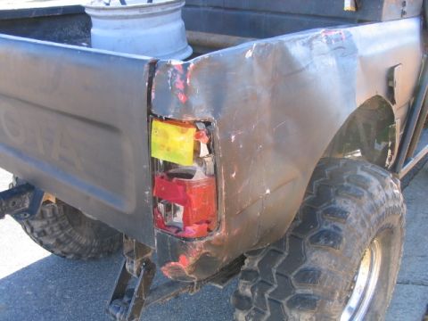 1986 Ford F-150 - The rear corner of a pickup truck shows significant damage to the taillight assembly and bodywork.
