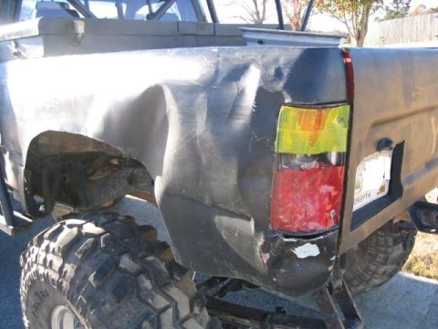 1986 Ford F-150 - The rear of a truck shows significant damage to the quarter panel and a jury-rigged taillight assembly.