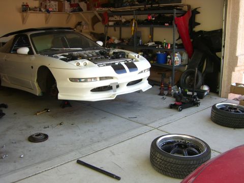 1996 Ford Probe - A white 1996 Ford Probe is undergoing maintenance in a cluttered garage.