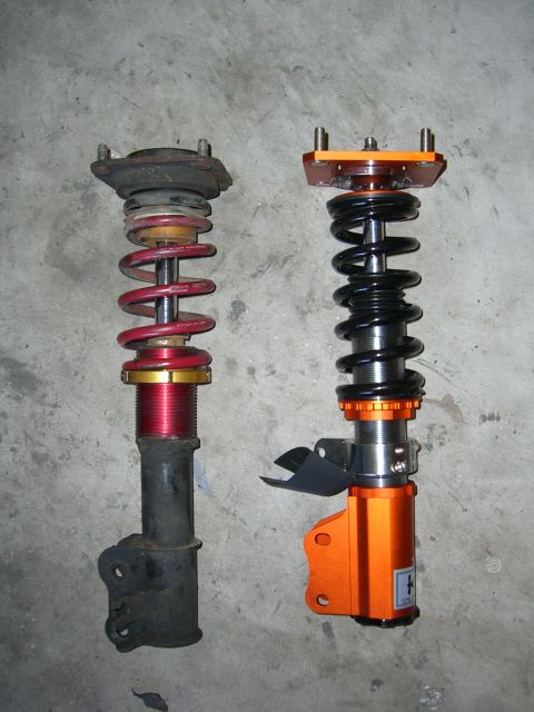 1996 Ford Probe - Comparison of two different car suspension strut assemblies, one appears older and worn, the other is a newer aftermarket part.