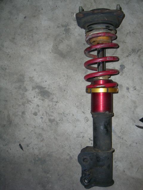 1996 Ford Probe - A red coilover suspension part is shown against a concrete surface.