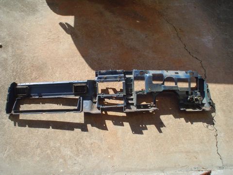 1984 Ford Bronco - This dashboard frame, likely from an older vehicle, is shown disassembled on a concrete surface.