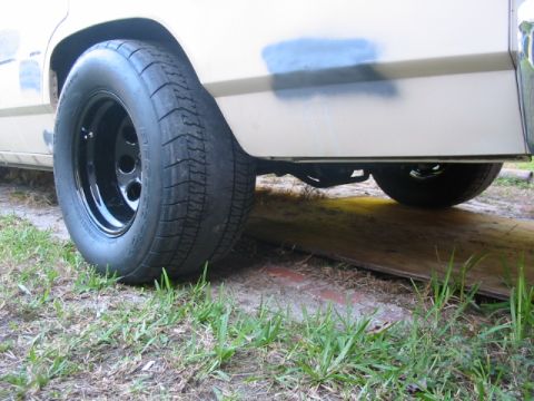 1985 Ford LTD Crown Victoria - Close-up of a rear wheel and tire on a white vehicle, with a patch of blue paint on the fender.