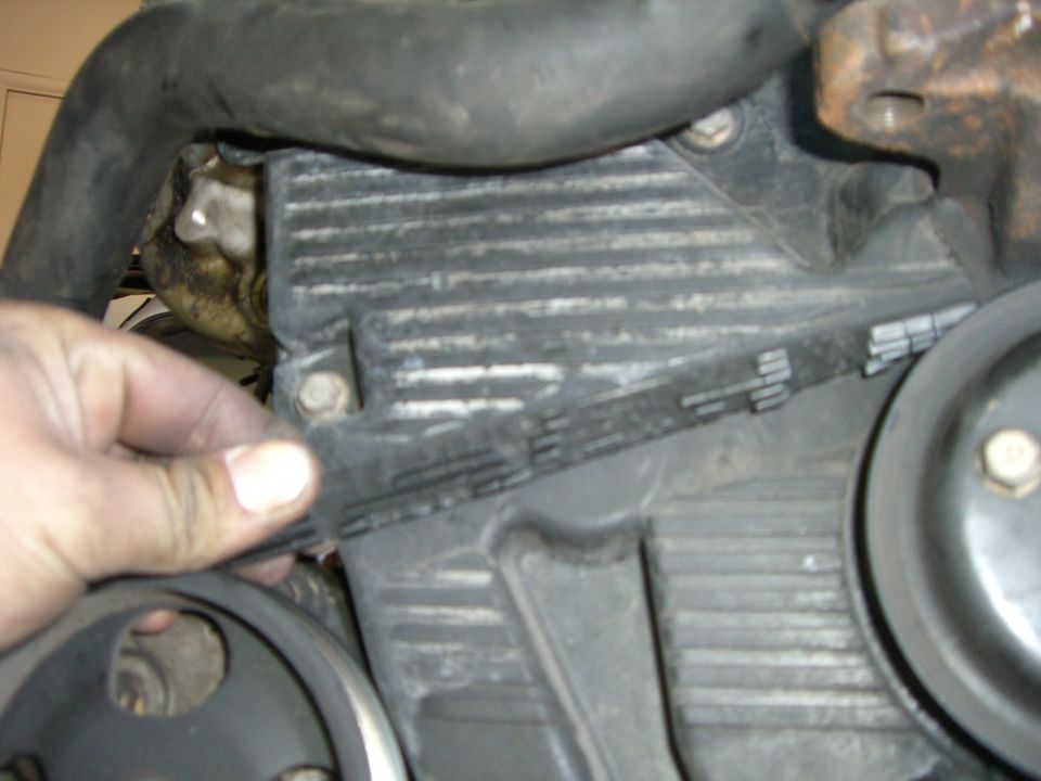 Hand checking timing belt tension on engine component