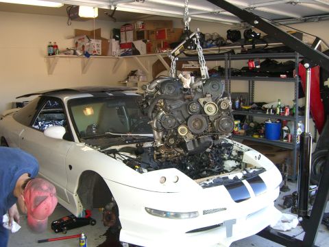 1996 Ford Probe - Engine removal in progress for a white car in a garage setting.