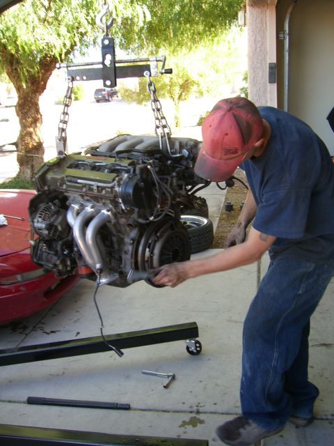 1996 Ford Probe - A V6 engine is removed from a red car with a hoist and engine crane.