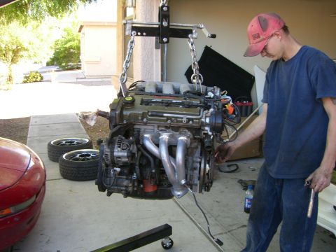 1996 Ford Probe - Engine removal or installation in progress with a person assisting.