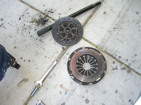 1996 Ford Probe - Car parts, a clutch disc and pressure plate, are laid out on the ground next to tools.
