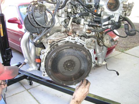 1996 Ford Probe - Engine and transmission assembly being worked on, with a portion of a red vehicle in the background.