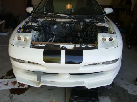 1996 Ford Probe - The front of a white coupe is shown with the hood open, revealing the engine compartment and various hoses and wires.