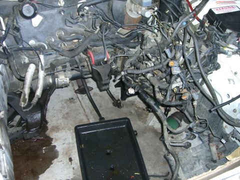 1996 Ford Probe - Disassembled engine bay reveals complex wiring and plumbing, with a drain pan collecting fluids.