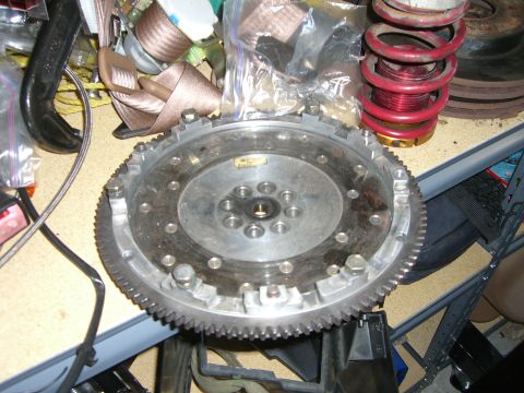 1996 Ford Probe - A car part, likely a flywheel, is shown on a cluttered workbench with other automotive components.