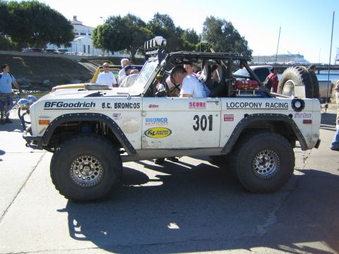 1990 Ford Bronco - Side profile of an early Ford Bronco off-road racer numbered 301 with 'Locopony Racing' and 'B.C. Broncos' lettering and a rear-mounted spa…