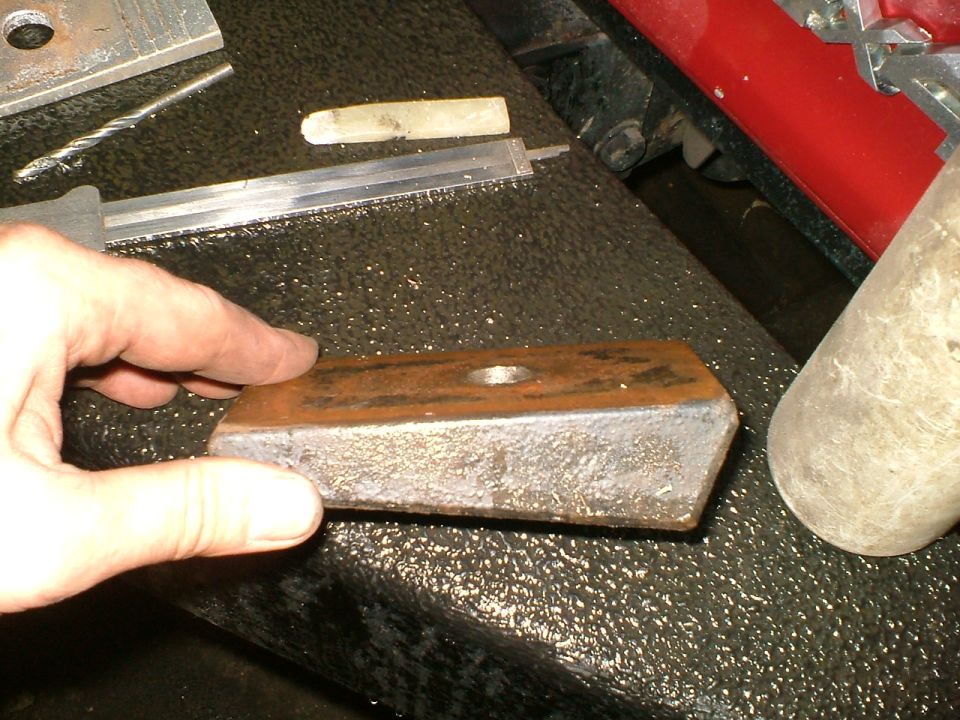 Hand holding a rectangular metal shim with a hole in the center
