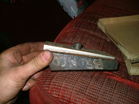 1989 Ford Bronco - A person holds a metal component, possibly a brake caliper or similar part, with a shim placed on top.