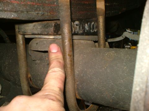 1989 Ford Bronco - A finger points to a shim being installed in the rear suspension of a vehicle, with "BRONCO" visible on a part.