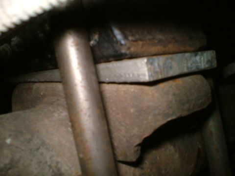1989 Ford Bronco - Close-up view of a metal shim being installed in a vehicle's rear end assembly.