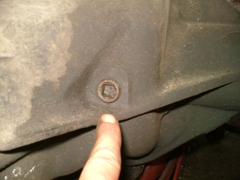 1989 Ford Bronco - A finger points to a square-headed plug on a vehicle's differential housing.