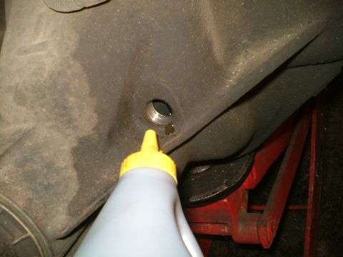 1989 Ford Bronco - A bottle dispenses fluid into a vehicle's rear differential, likely for maintenance or repair.