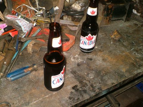 1989 Ford Bronco - Two bottles of Molson Canadian beer sit on a workbench covered in tools and debris.