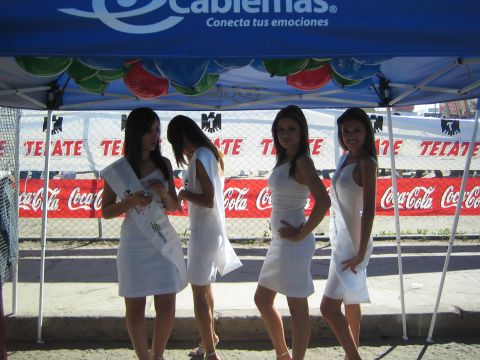 1990 Ford Bronco - Four promotional models in white dresses pose beneath a blue Cablemas canopy in front of Tecate and Coca-Cola banners.