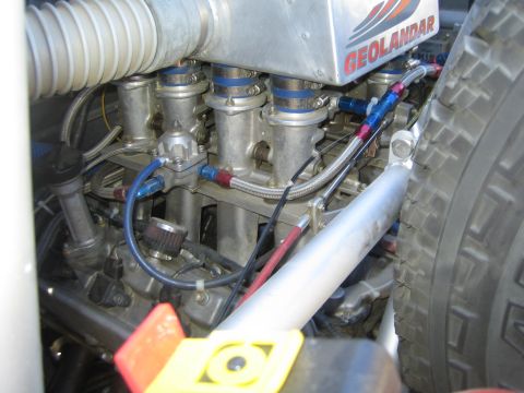 1990 Ford Bronco - Detailed engine bay shot showing individual throttle bodies, braided fuel lines and a Geolandar decal on a race vehicle.