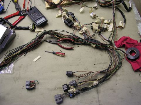 1996 Ford Probe - A complex automotive wiring harness is laid out on a workbench alongside various tools used for electrical work.