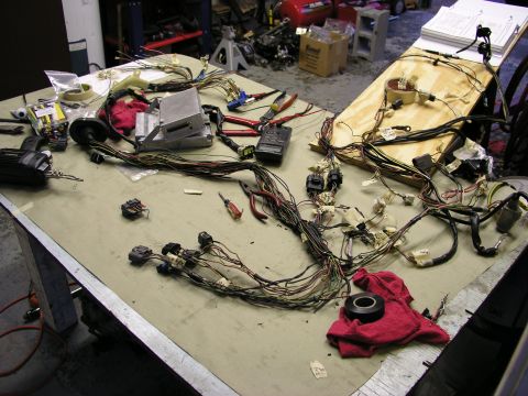 1996 Ford Probe - A disassembled car wiring harness is spread across a workbench, surrounded by tools and electrical components.