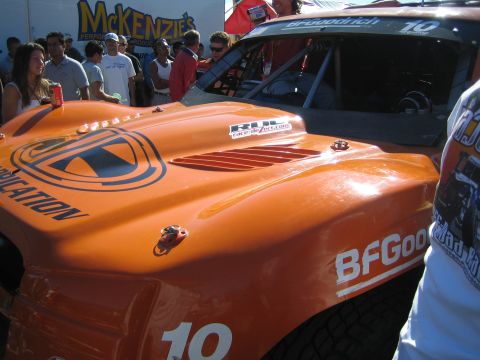 1990 Ford Bronco - Close view of an orange off-road race car's hood marked with BFGoodrich and number 10 as spectators stand around it.