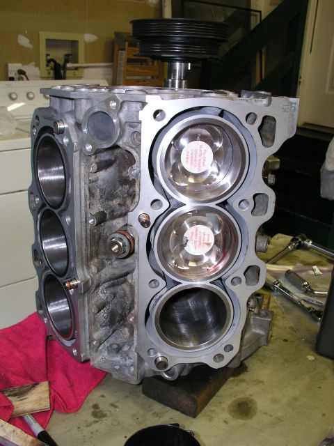 1996 Ford Probe - Engine block assembly with pistons and a pulley system, resting on a wooden block.