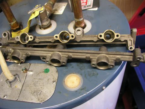 1996 Ford Probe - Two metal fuel rails are shown on top of a water heater, likely during a repair or rebuild process.